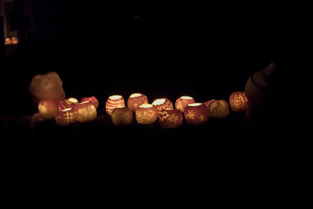 Eine Reihe von geschnitzten Räbeliechtli auf dunklem Boden