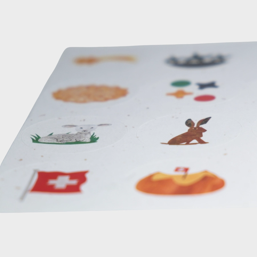 Nahaufnahme von runden Stickern mit Schweizer Motiven wie Fahne und Lamm für Projektarbeiten und Agenda-Gestaltung.