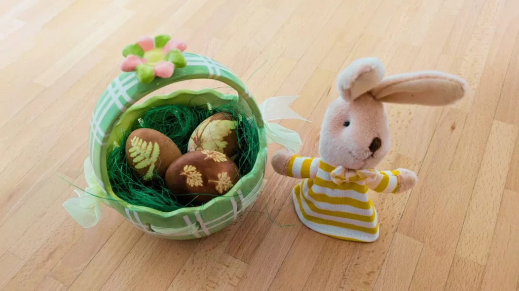 Grüner Osterkorb mit natürlich gefärbten Eiern und Plüschhase