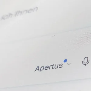 Eine detaillierte Nahaufnahme eines Suchfelds mit dem Namen "Apertus", einem blauen Dropdown-Pfeil und einem Mikrofon-Icon für die Sprachsteuerung.