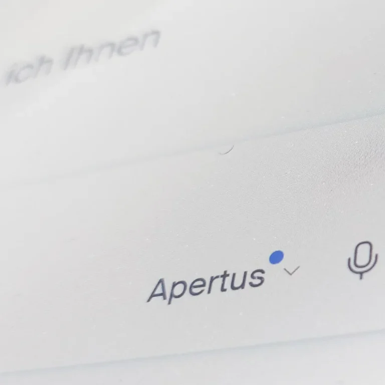 Eine detaillierte Nahaufnahme eines Suchfelds mit dem Namen "Apertus", einem blauen Dropdown-Pfeil und einem Mikrofon-Icon für die Sprachsteuerung.